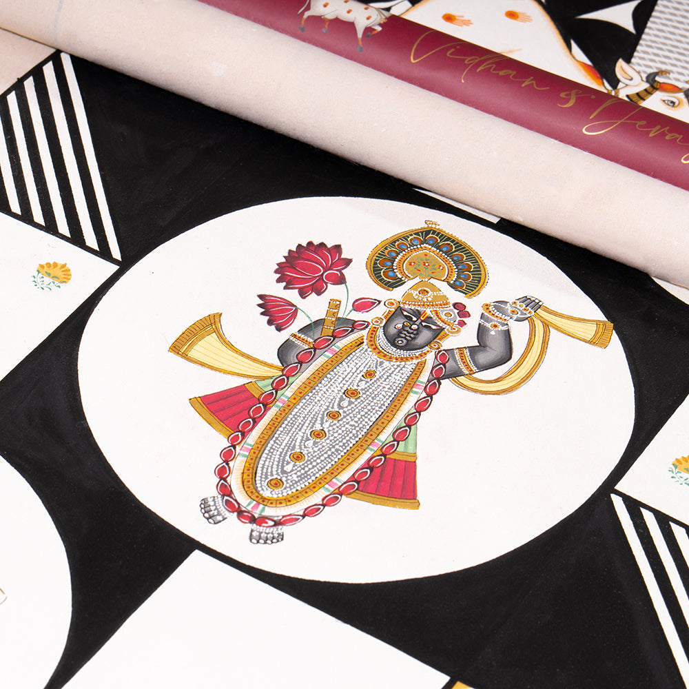 Luxury wedding invitation featuring hand-painted Pichwai artwork of Lord Krishna with lotus and shankha, elegant black and white design.