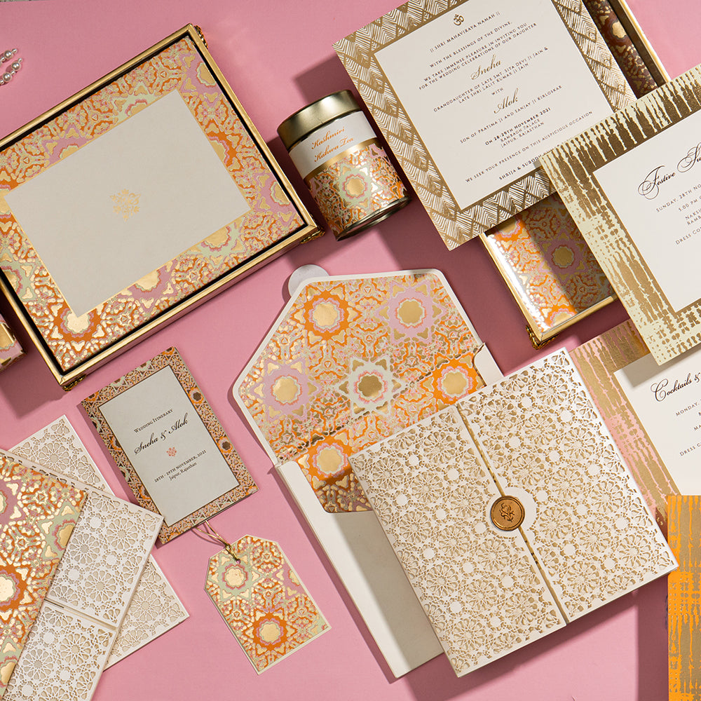 Opulent gold-foiled wedding invitation suite with intricate Mughal-inspired patterns, premium gift boxes, and matching tags.