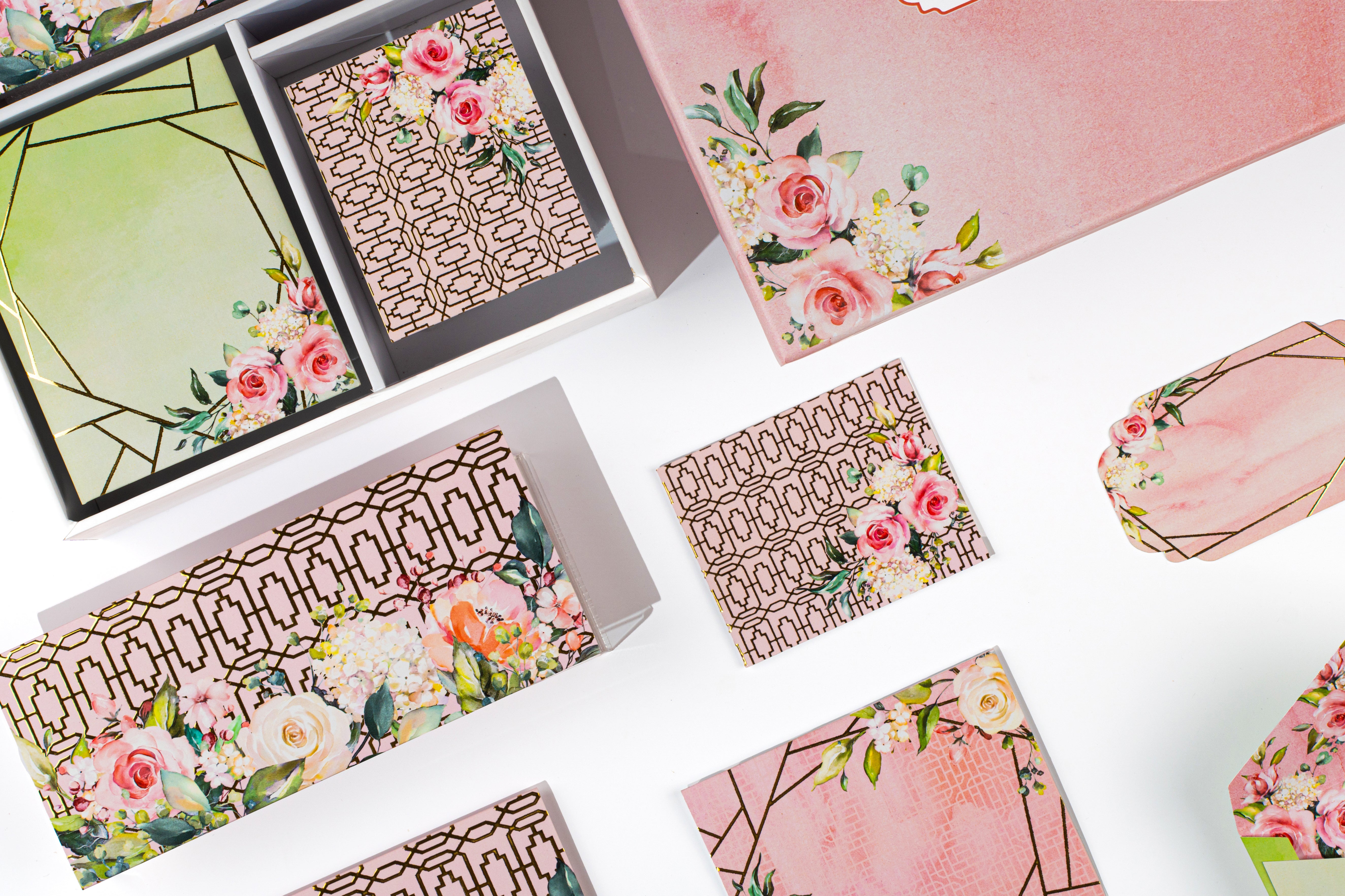 Elegant rose-themed stationery collection with pastel pink boxes, botanical prints, patterned envelopes, and coordinated gift tags.