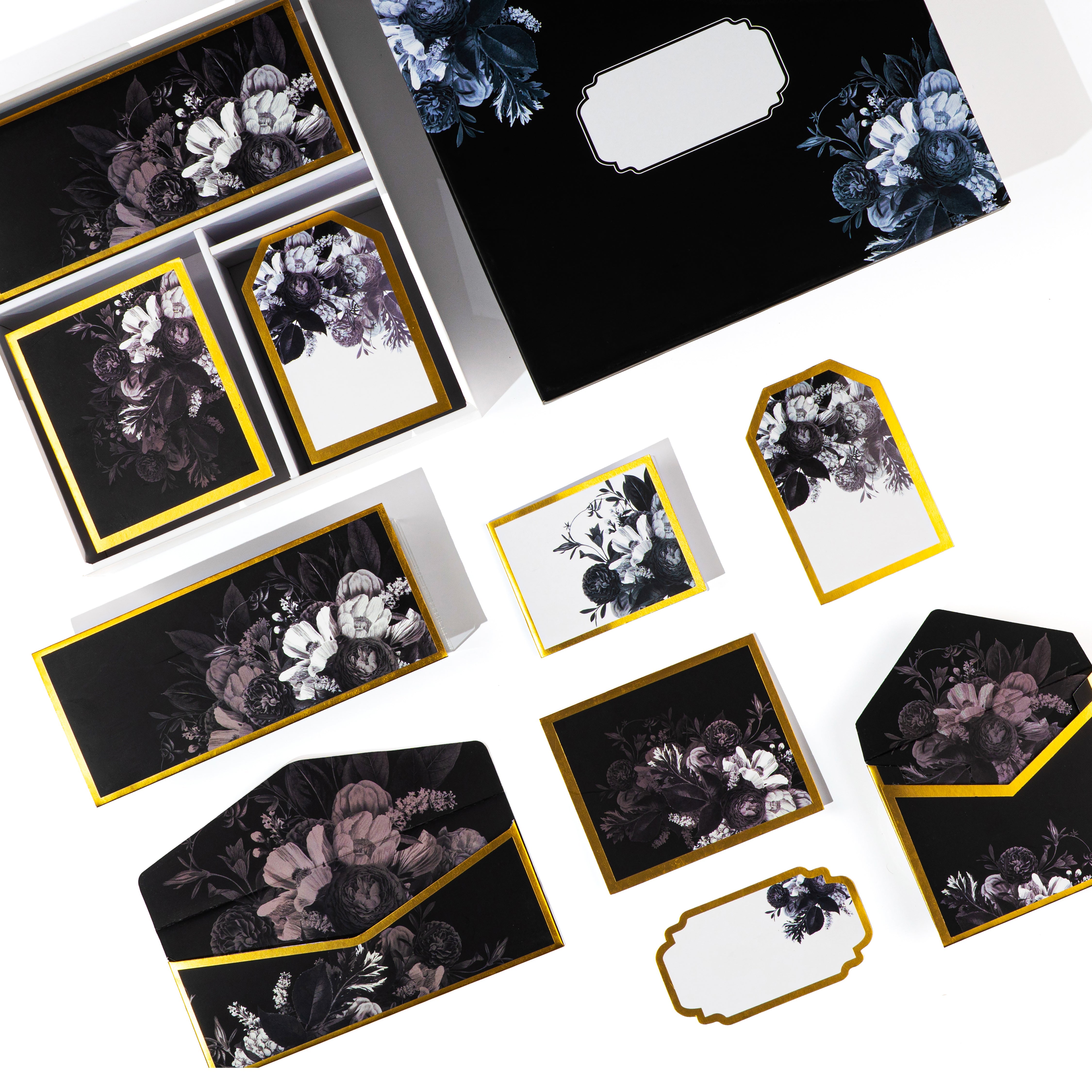 Luxury black floral stationery set with envelopes, cards, and boxes featuring gold trim and elegant botanical designs.