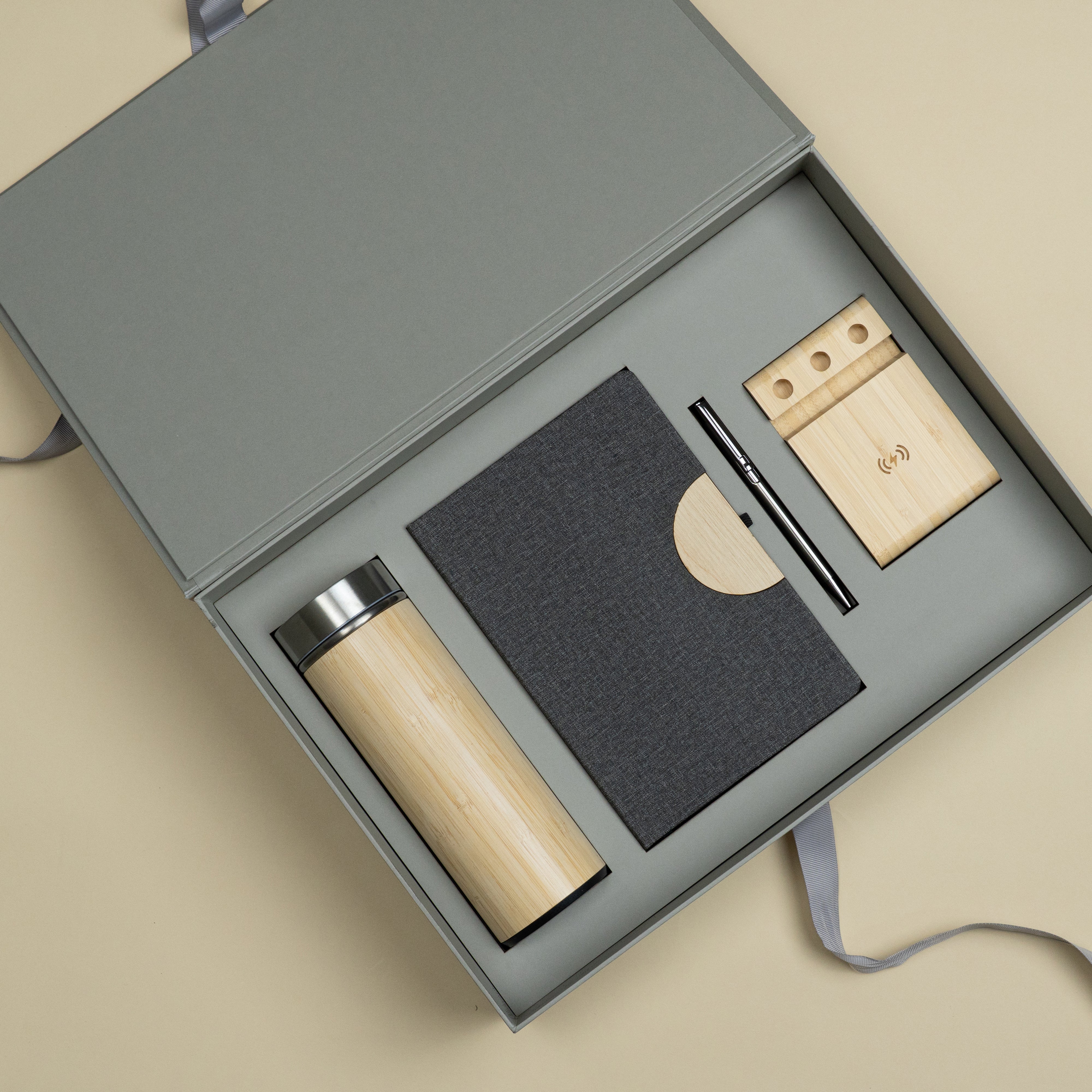 Premium corporate gift set featuring a diary, metallic pen, bamboo bottle and wireless bamboo phone charger with stand in a customized cardboard gift box.