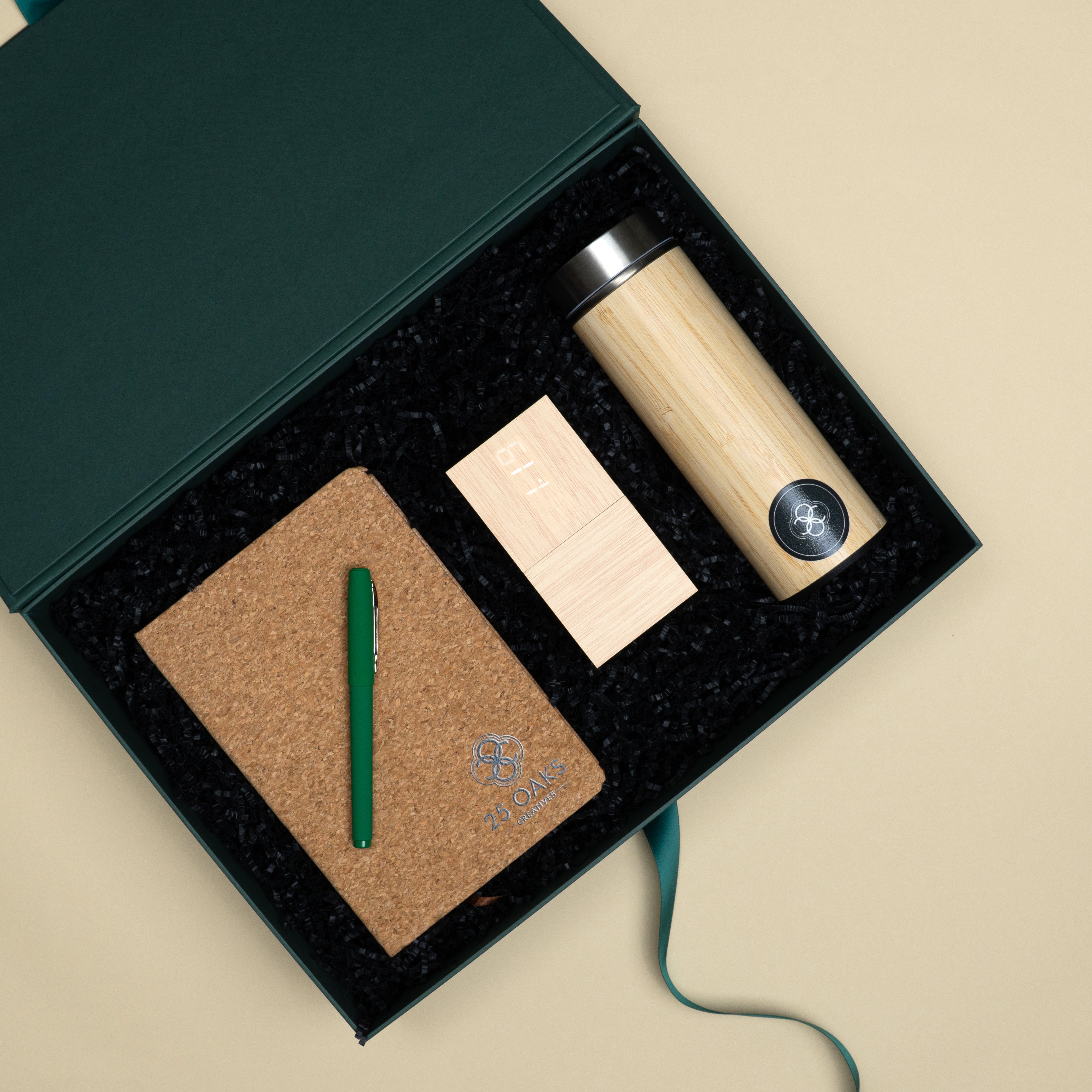 Premium corporate gift set featuring a green matte pen, cork diary, bamboo table clock and bamboo bottle in a luxury presentation box.