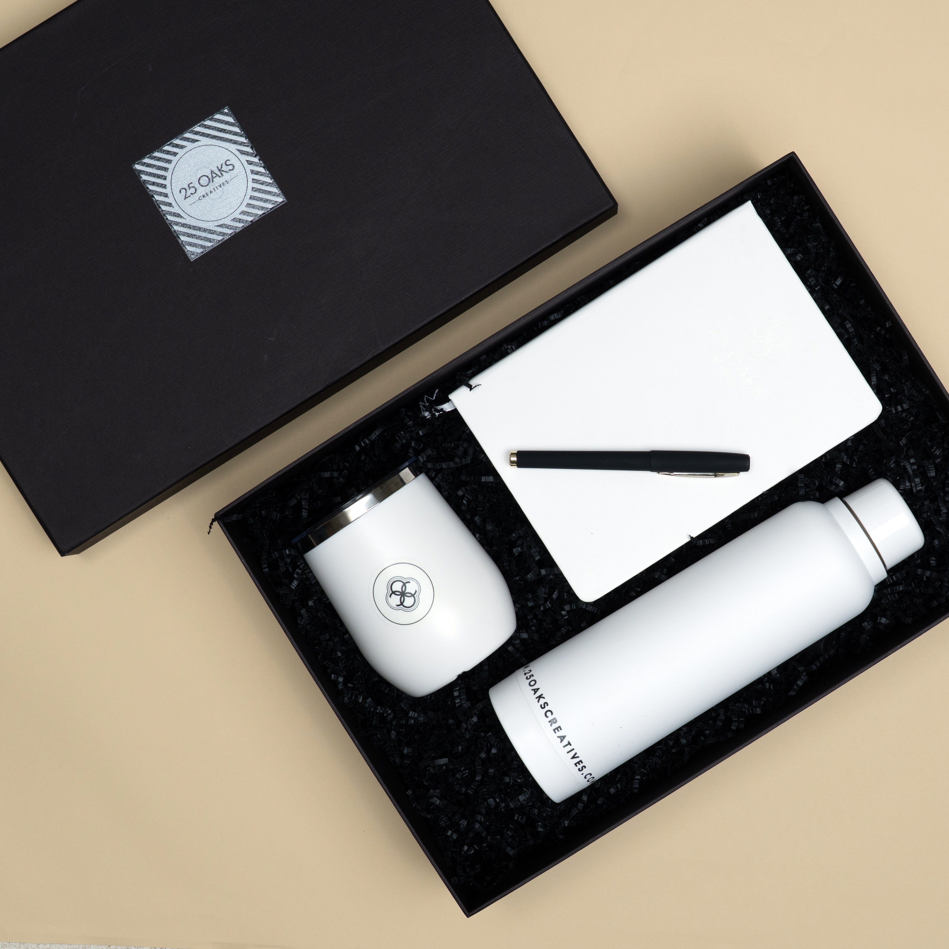 Premium corporate gifting set featuring a black pen, A5 white notebook, insulated vacuum flask mug and white water bottle.