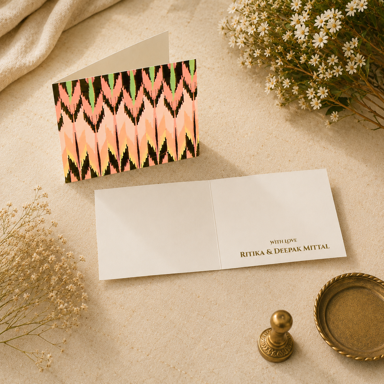 Modern pastel ikat folded card with abstract patterned artwork and elegant ivory interiors styled with soft floral props.