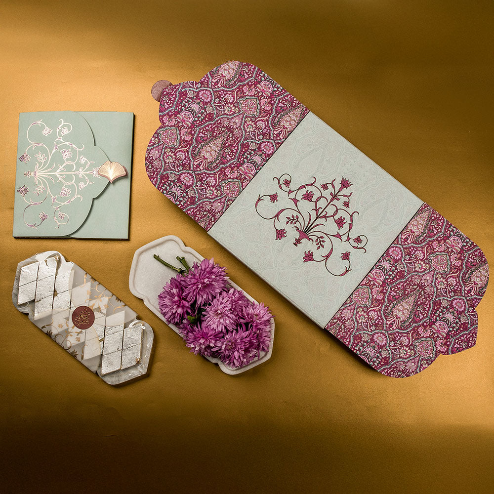 Opulent paisley patterned wedding invite with maroon and beige box and floral tray.