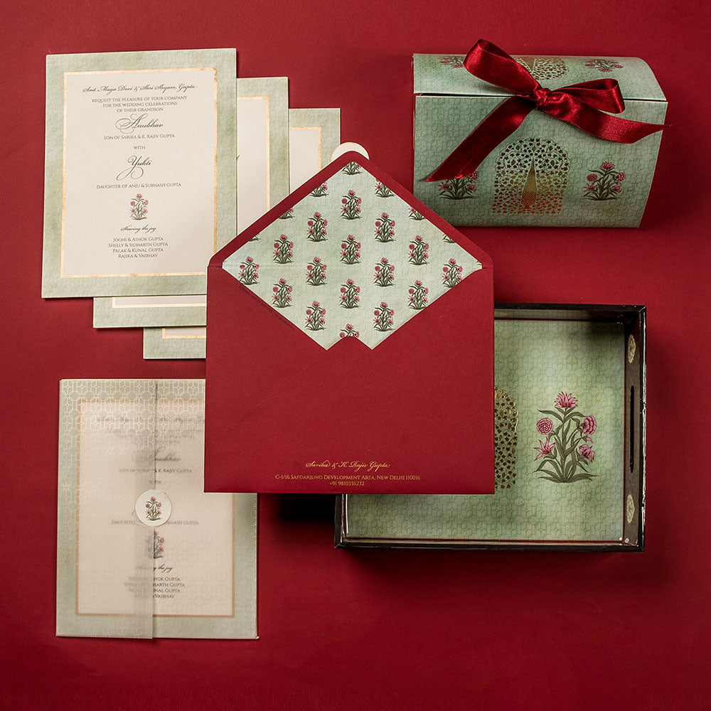 Elegant Mughal-inspired wedding invite set with green and red palette and floral motifs.