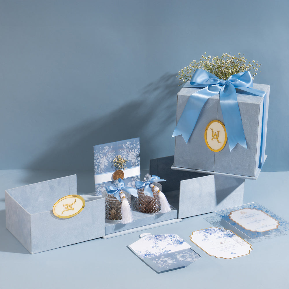 Blue velvet invitation and favor box with ribbon, wax seals, and floral accents