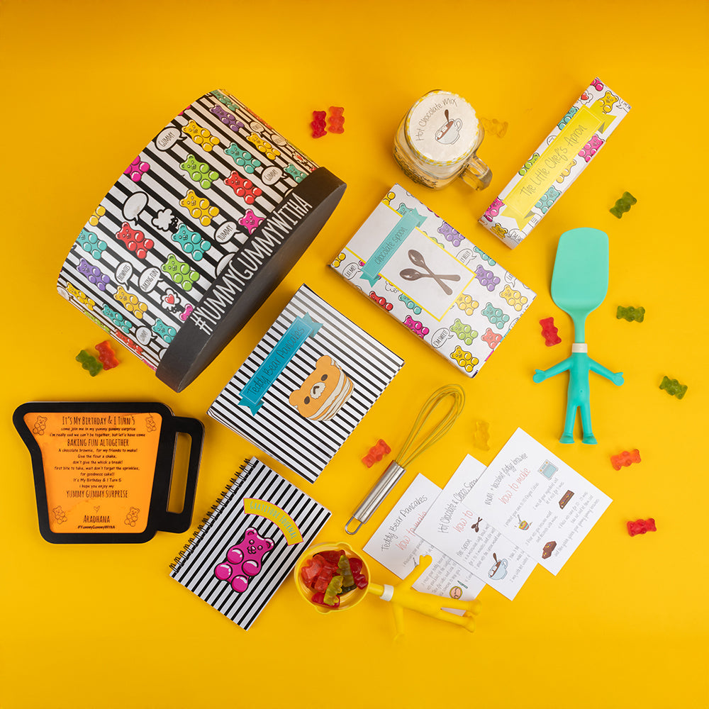 Gummy bear-themed baking return favour box with apron, cupcake mix, and DIY tools for kids.