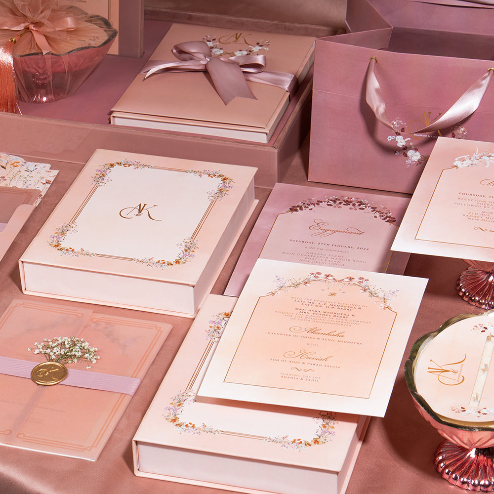 Blush pink wedding invite set with wax seals, velvet drawers, candles, and floral date bags.  