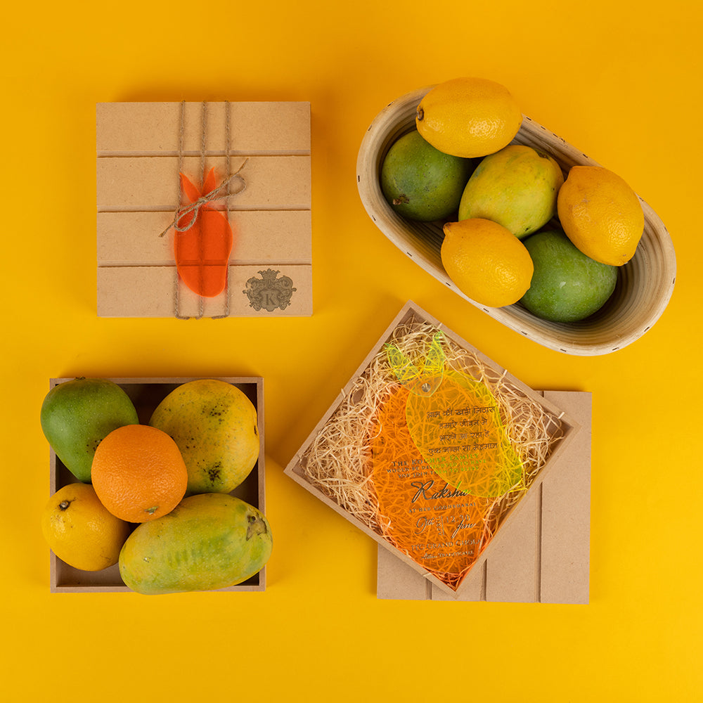 Mango-shaped baby shower invite in wooden crate with hay, inspired by summer godh bharai celebration and Indian traditions