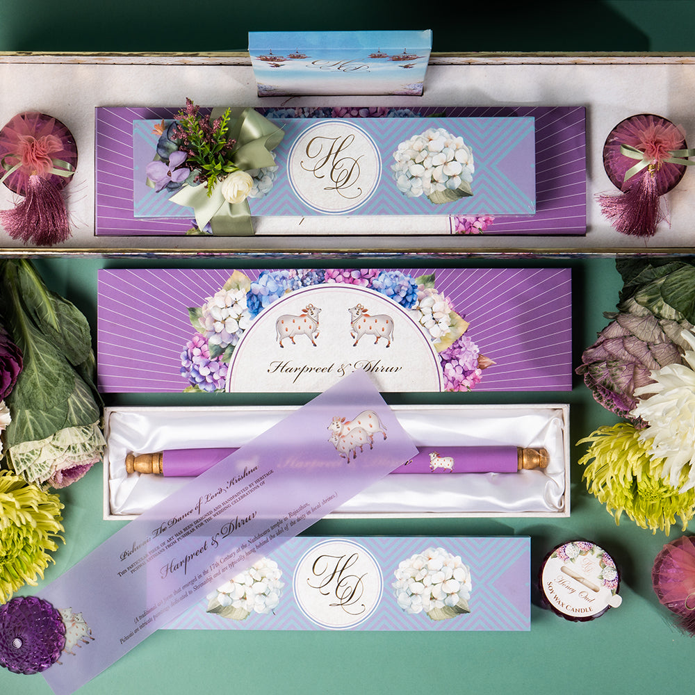 Wedding tray with candles, scroll invite, Ludhiana sweets, and Pichwai card in a floral box.