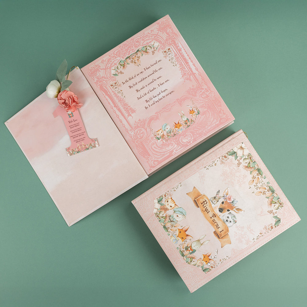 Fairytale birthday invite box with woodland illustrations, treats, and floral “1” tag. 