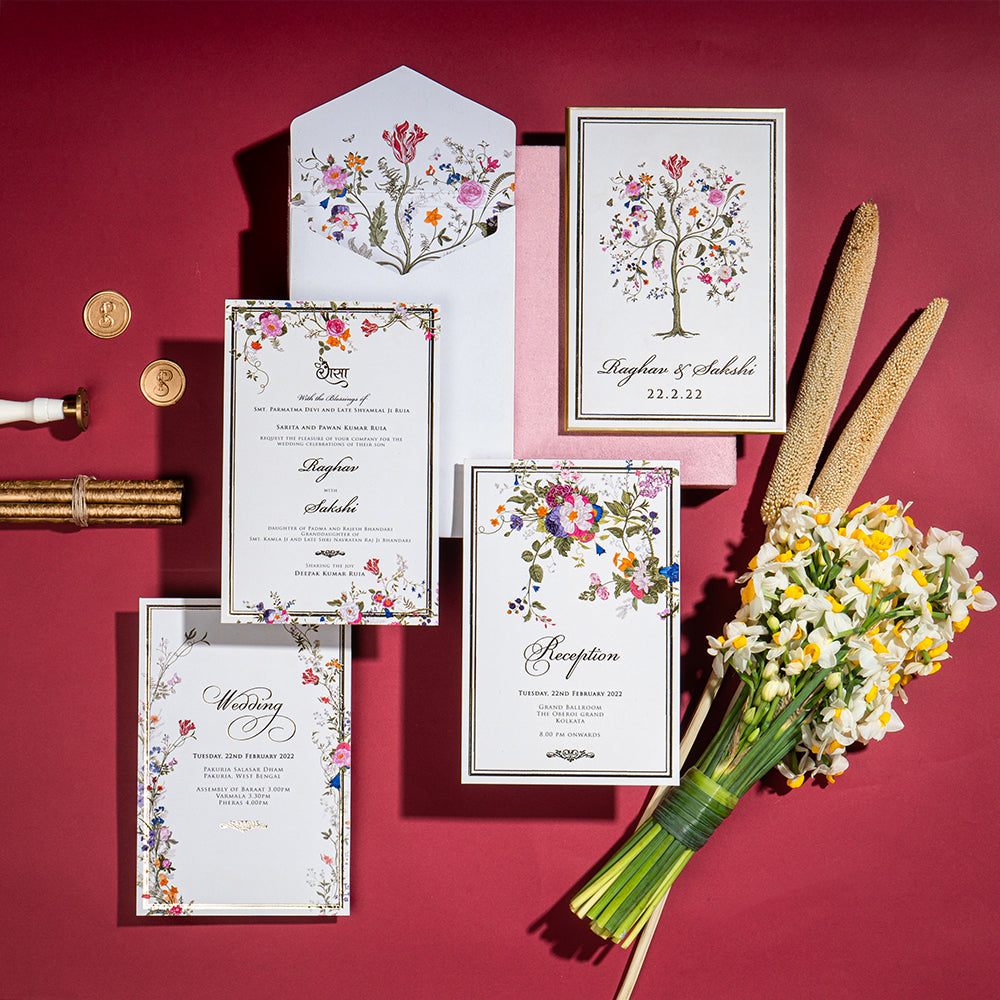 Mughal floral wedding invite with blush, maroon, and gold accents.