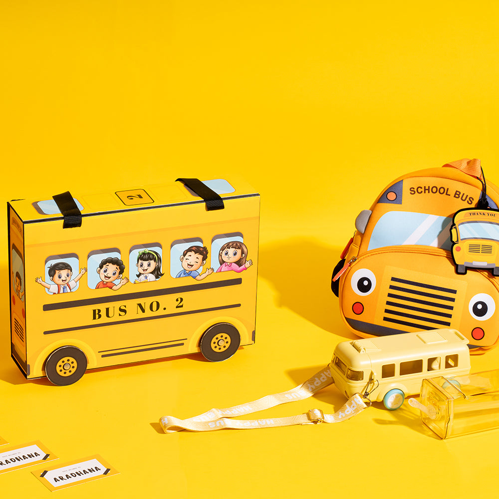 School bus-themed birthday favour box with toy wheels, bottle, bag, floaty, and name tags.