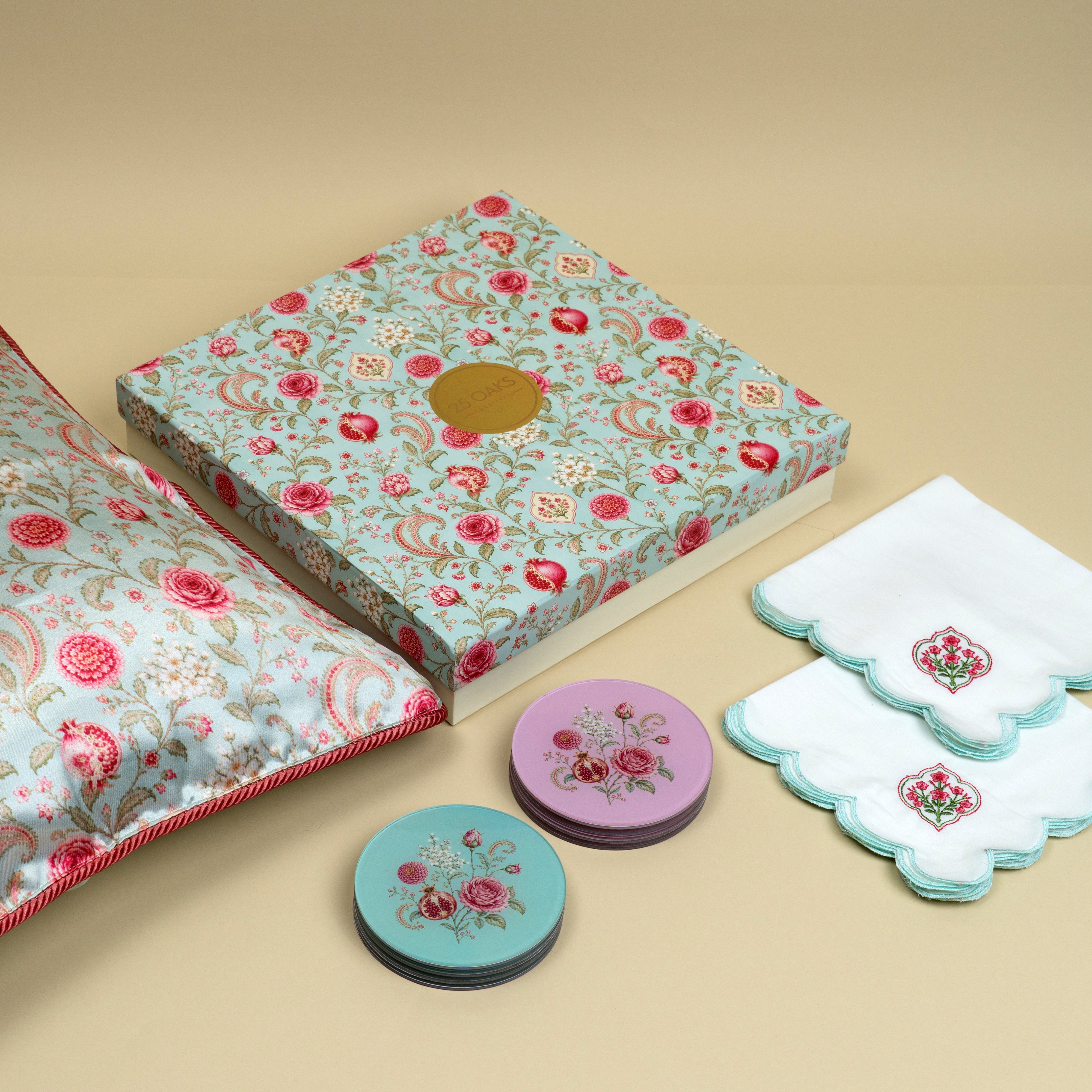 Festive home gifting set featuring decorative cushion covers, cocktail napkins and floral coasters