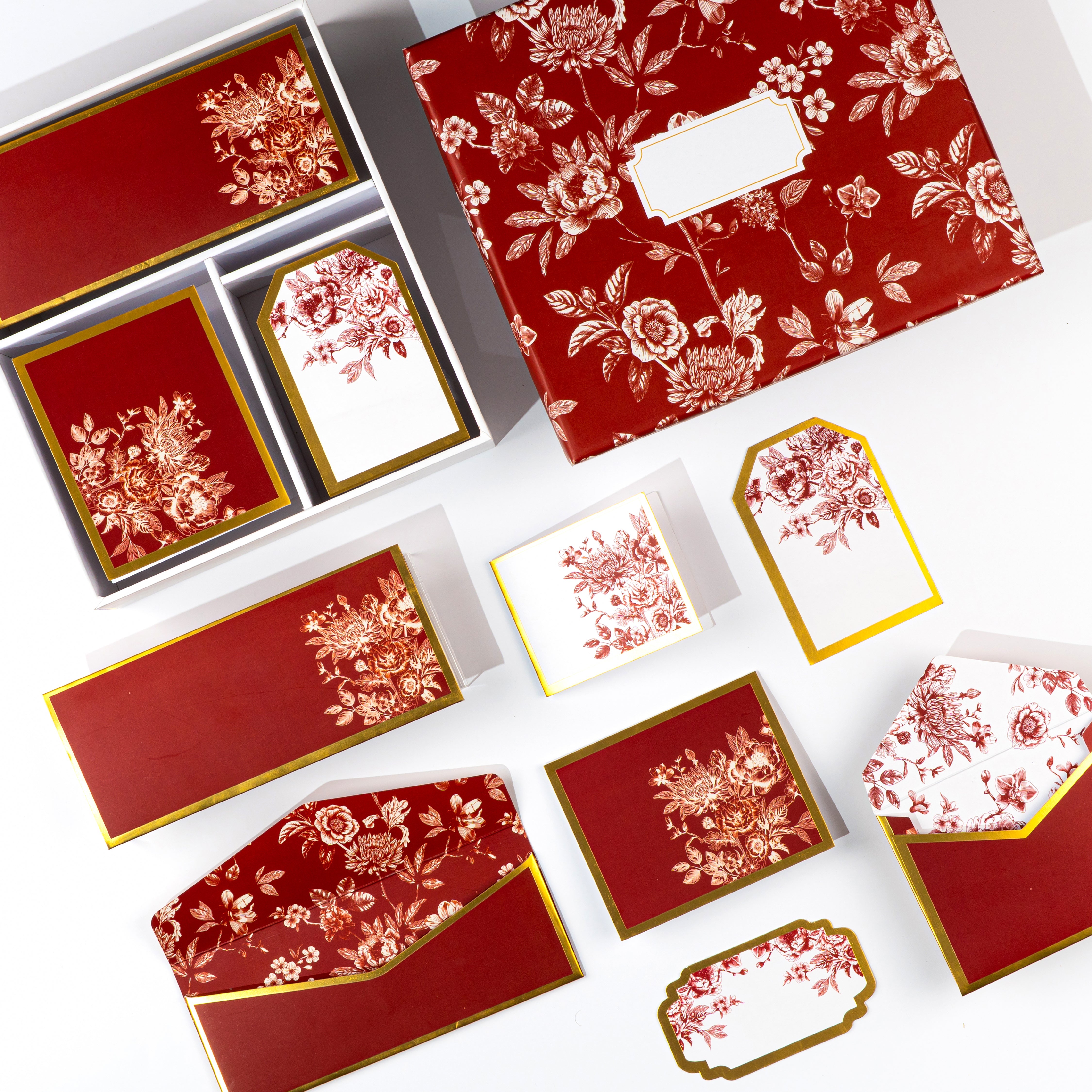 Elegant red and gold boxed stationery with rose‑patterned cards, envelopes, and tags.