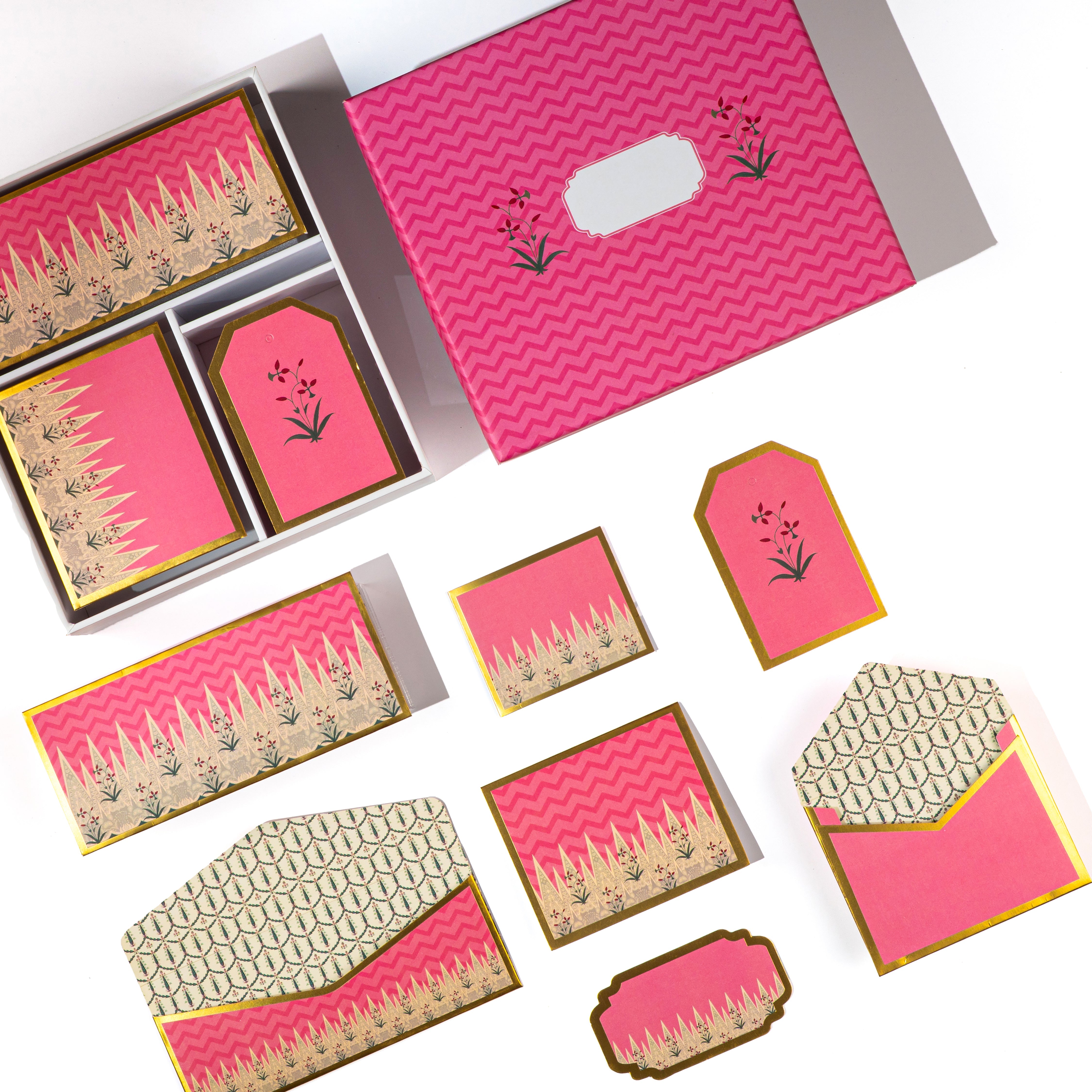 Pink Mughal-style stationery set with gold floral detailing, includes cards, tags, and patterned envelopes.