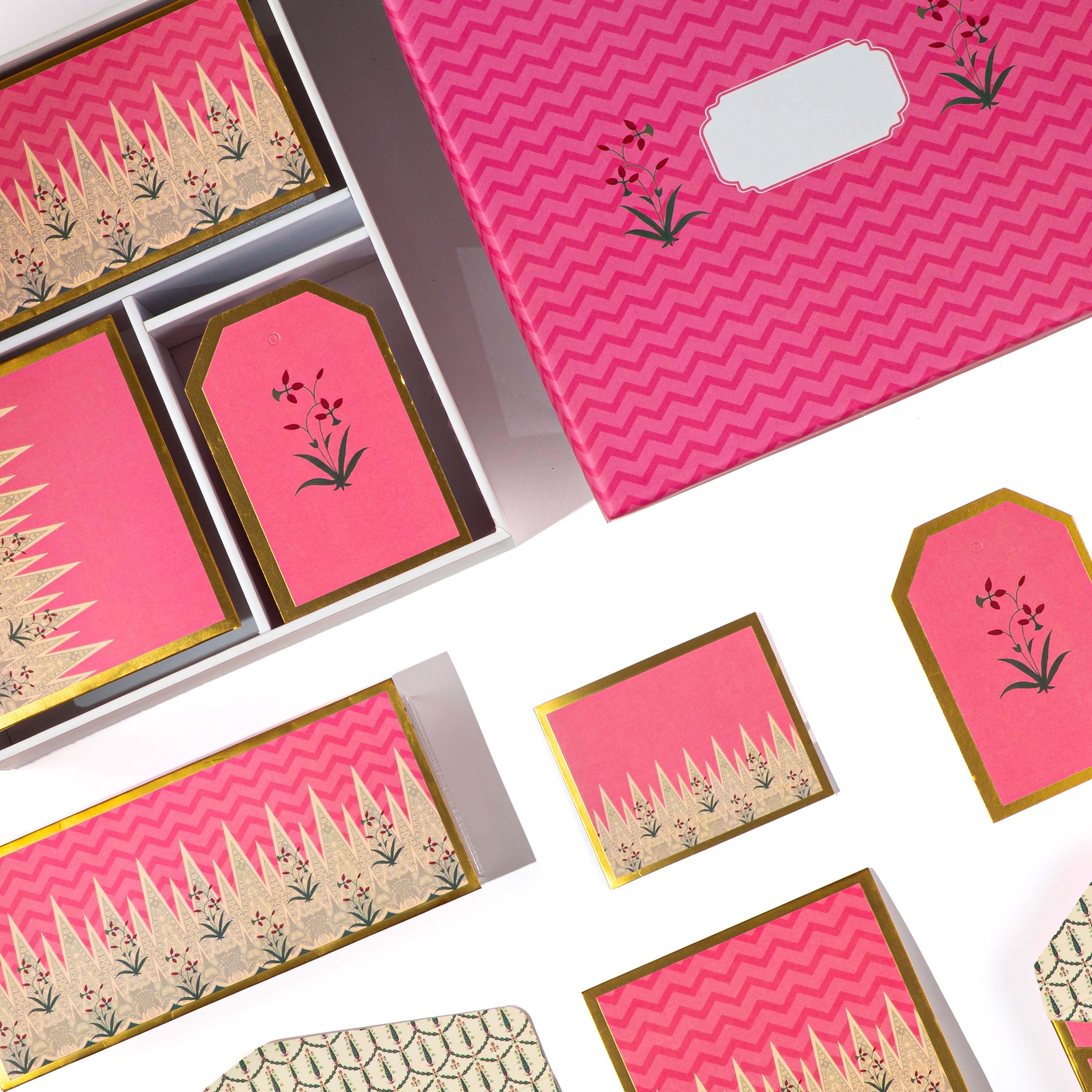 Pink Mughal-style stationery set with gold floral detailing, includes cards, tags, and patterned envelopes.