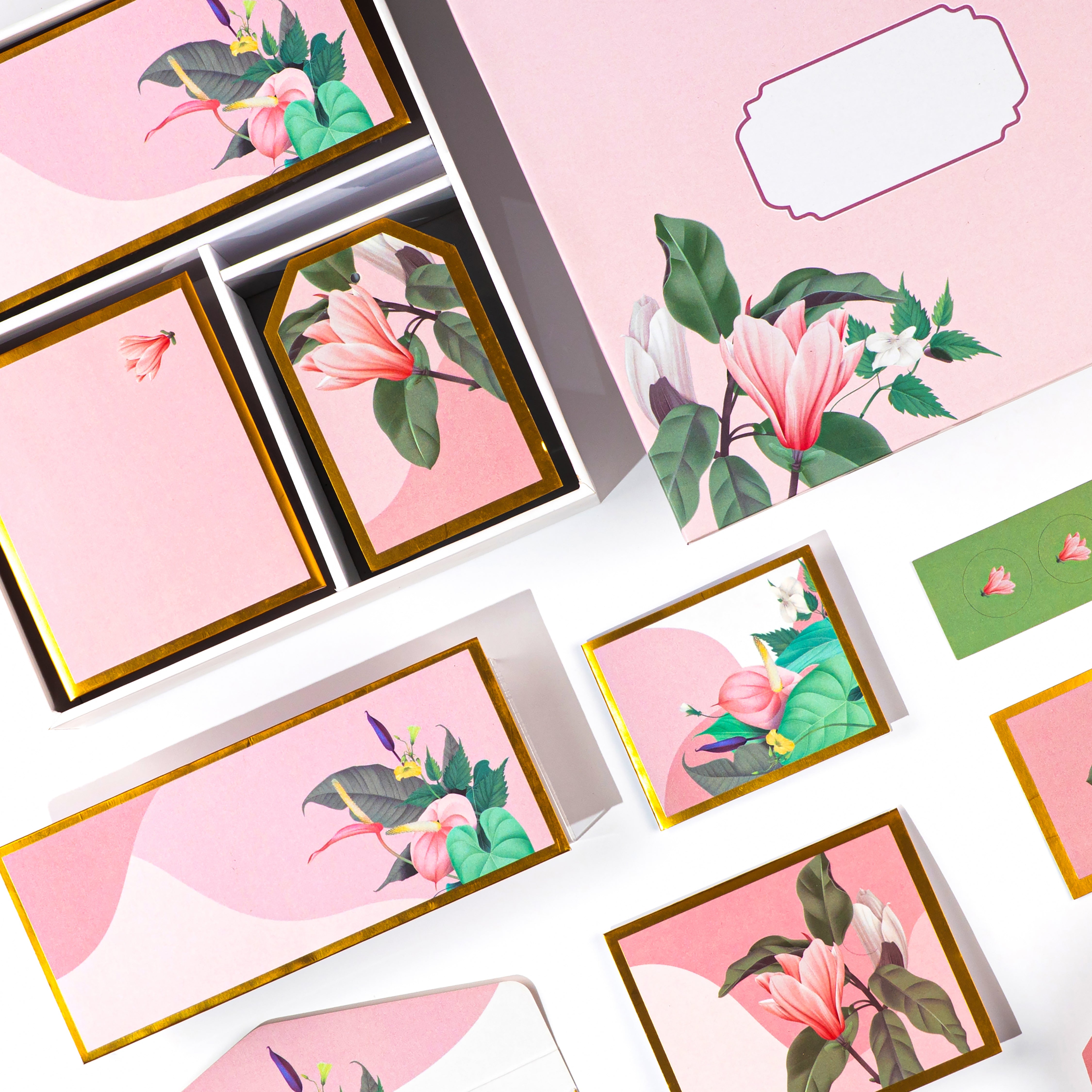 Elegant pink floral stationery set with lily illustrations, envelopes, tags, and folded cards.

