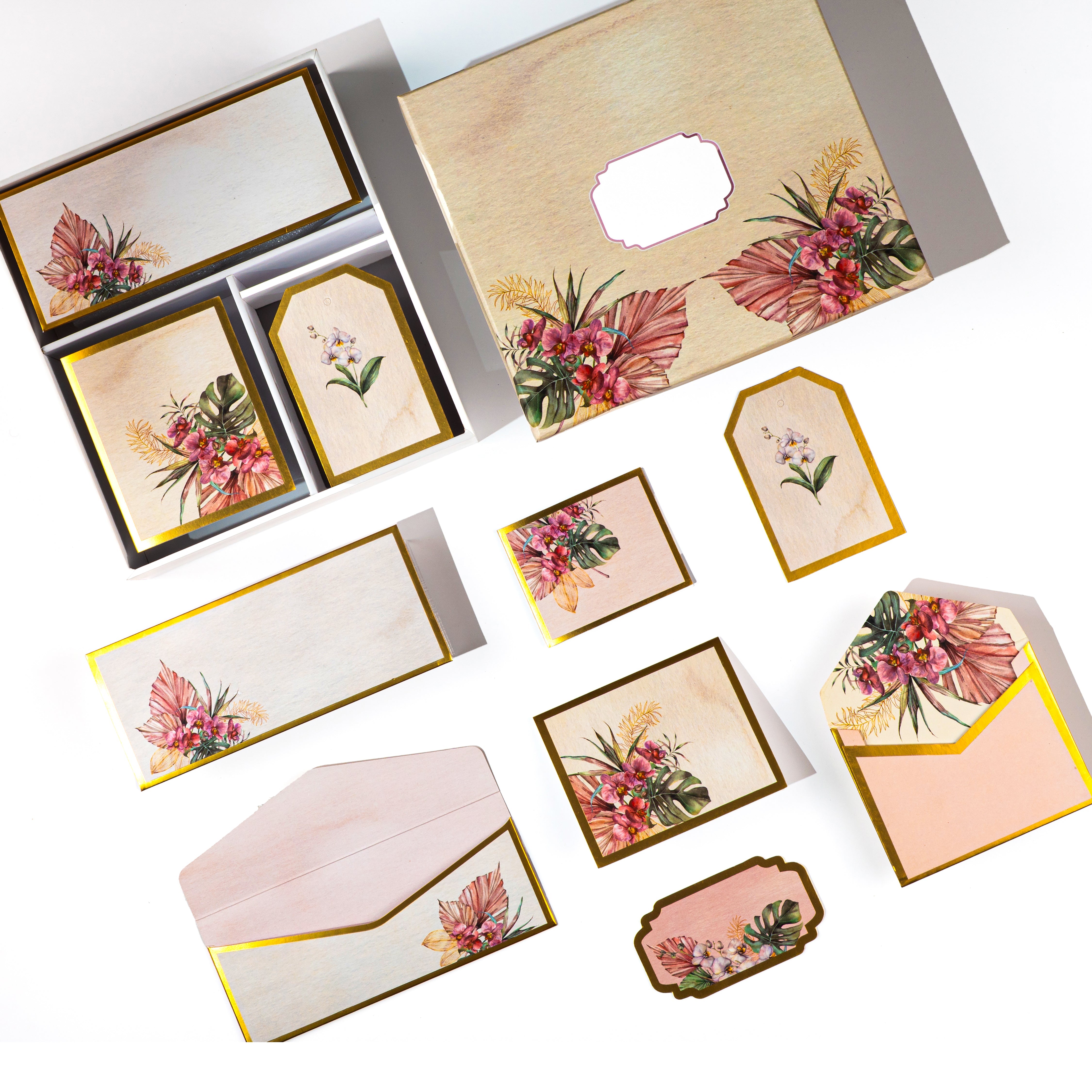Tropical floral stationery set with gold accents, featuring tags, cards, and envelopes in a wooden-look box.