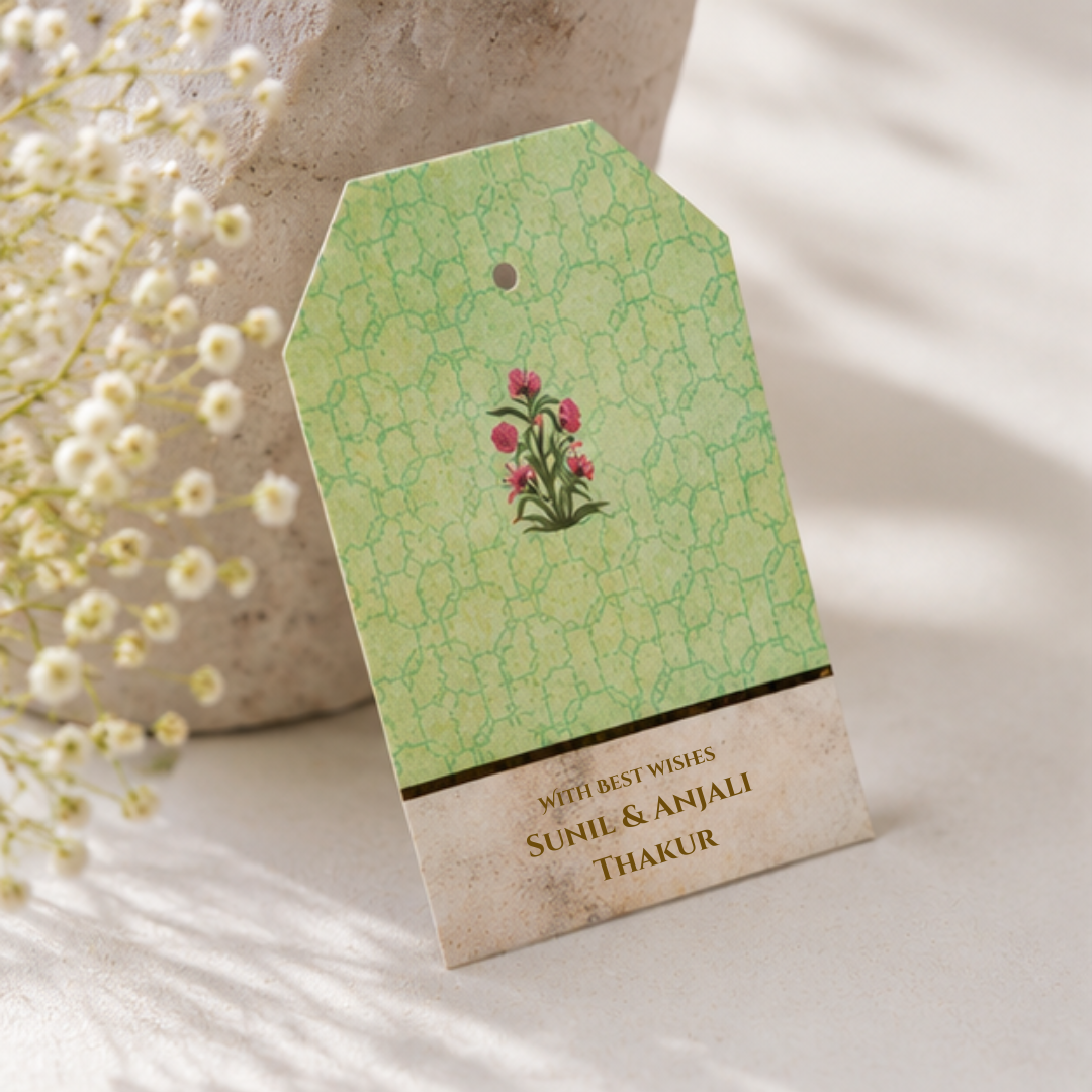 Elegant sage green hanging gift tag with delicate floral artwork and golden dori, styled in a luxury neutral-toned photoshoot.