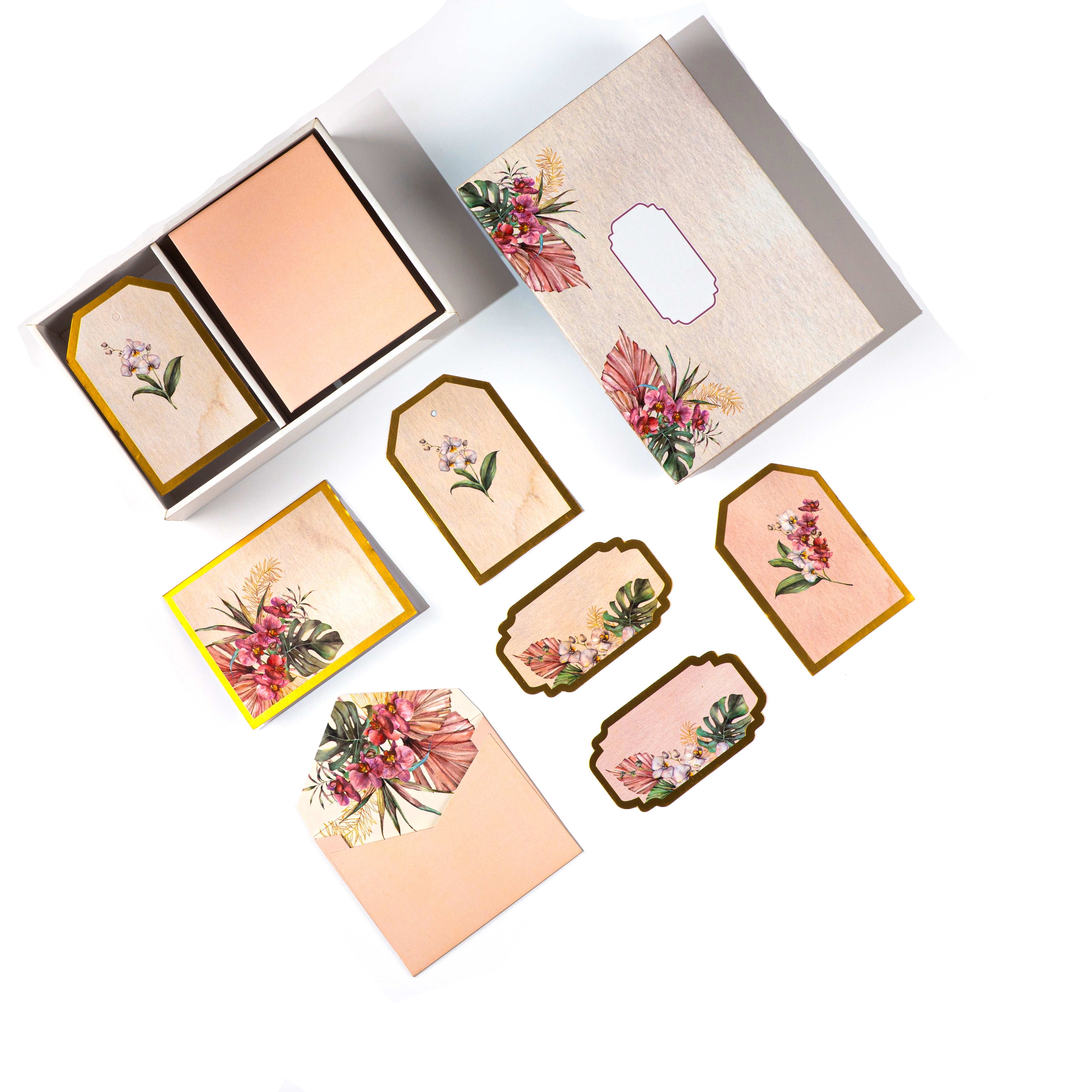 Tropical floral stationery set with gold accents, featuring tags, cards, and envelopes in a wooden-look box.
