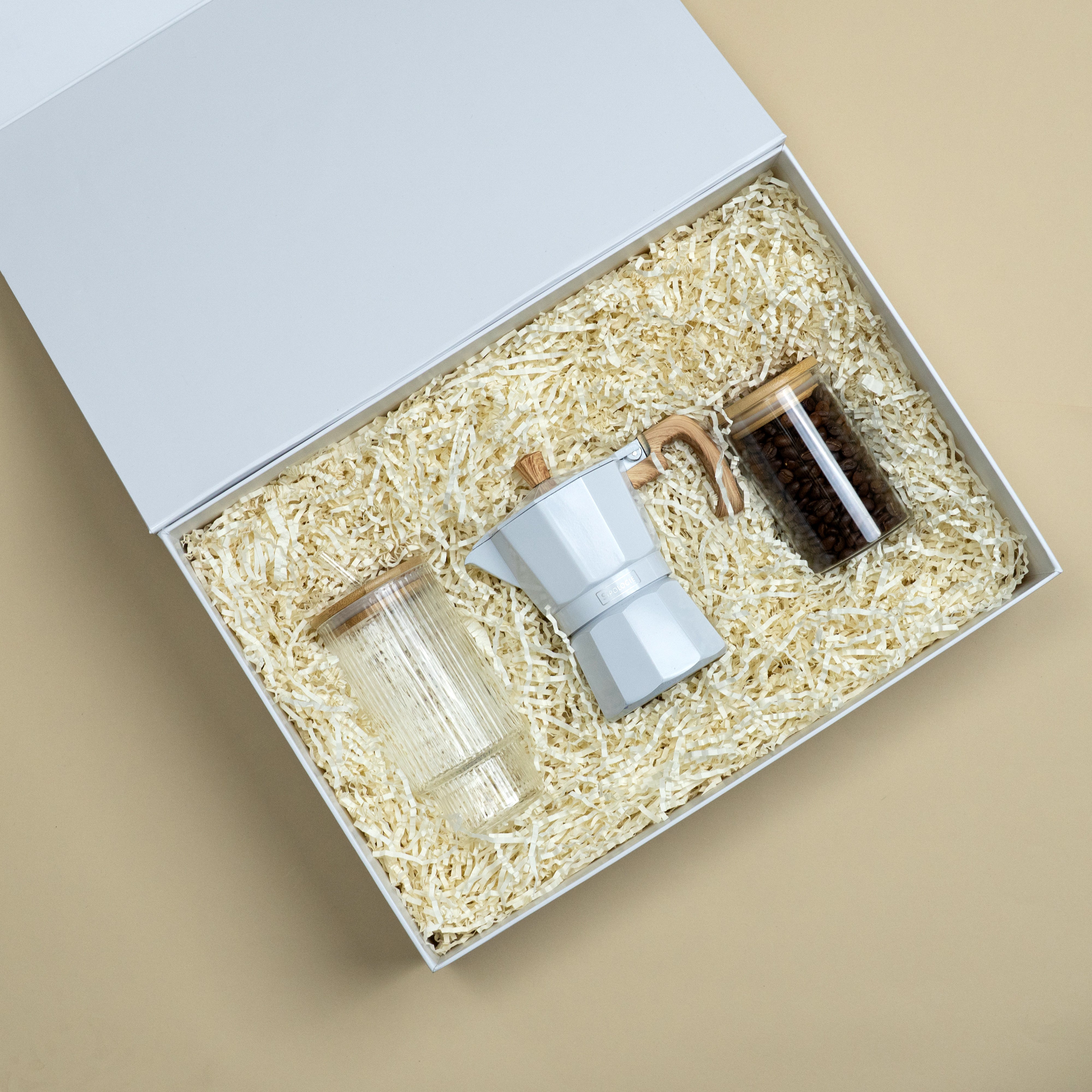 The Daily Grind coffee gift set with a white moka pot and two glass coffee storage jars in premium gift box packaging.