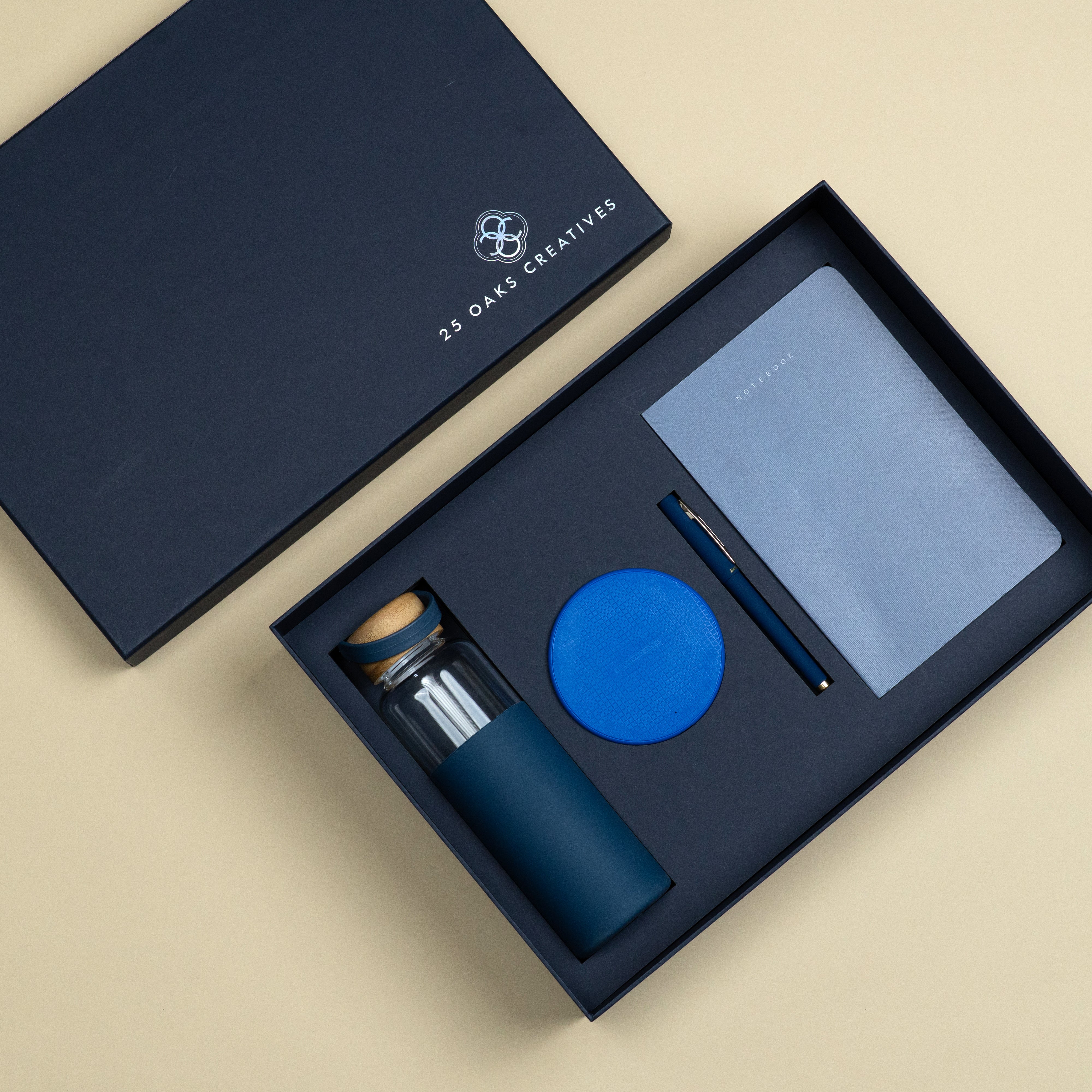 Blue corporate gift set with glass bottle, wireless charger, A5 notebook and matte blue pen.