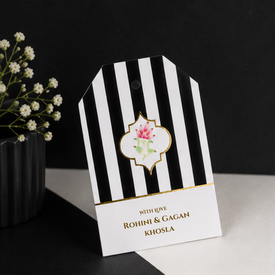 Elegant black and white striped hanging gift tags with gold detailing and floral motif, styled in a modern luxury photoshoot.